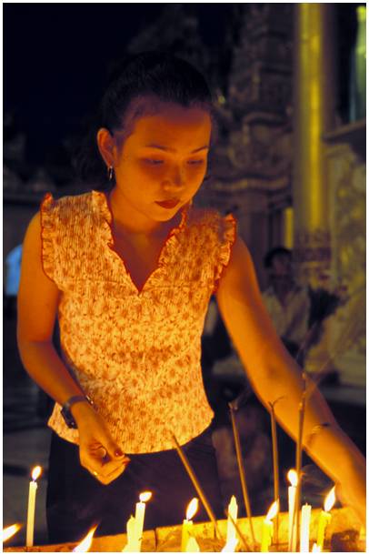 jeune femme allumant des bougies à la pagode Shwedagon au Myanmar